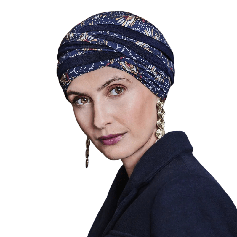 Turban Shanti imprimé Amber Garden porté par une femme, montrant la coiffure bleu foncé avec motif de plumes et de tiges