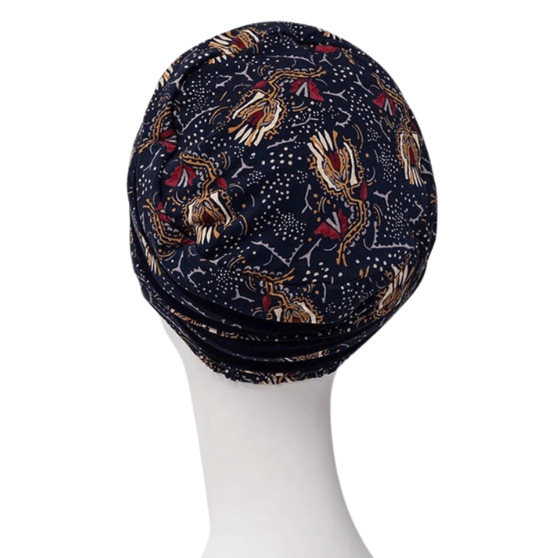 Turban Shanti imprimé Amber Garden vu de dos sur un mannequin blanc, avec le motif bleu foncé de plumes et de tiges