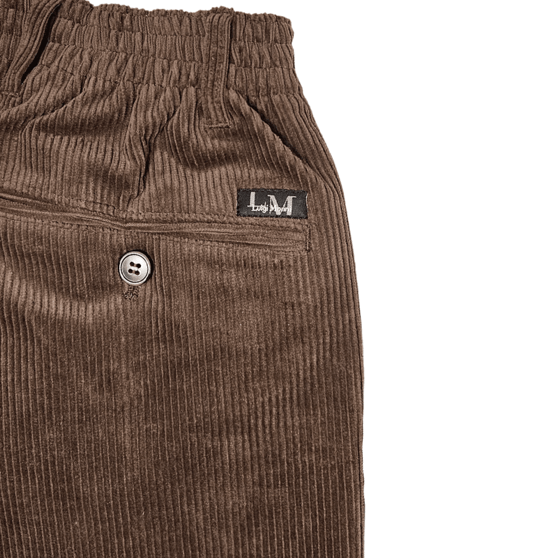 Détail gros plan du velours côtelé marron, taille élastique, passant, poche arrière boutonnée et étiquette de marque