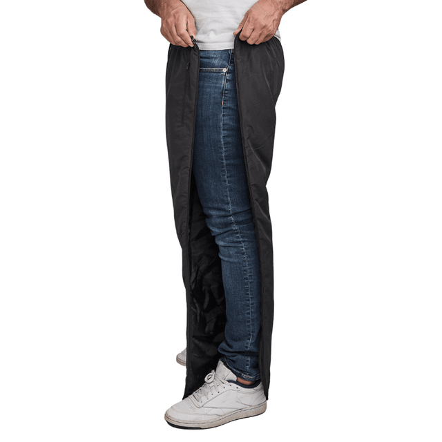 Homme ouvrant un pantalon thermique Dobsom noir sur le côté, par-dessus un jean bleu et des baskets blanches